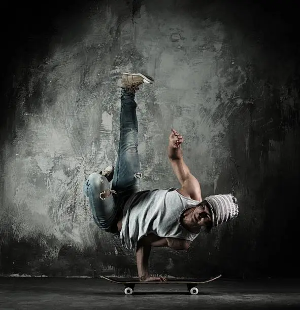 Young b-boy man doing brake dancing movements on skateboard