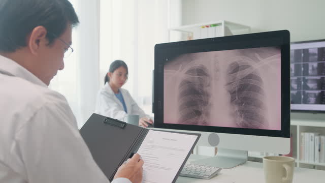 Adult Asian male doctors medical checking lung x-ray image of patient on computer screen in hospital. Medical health care.