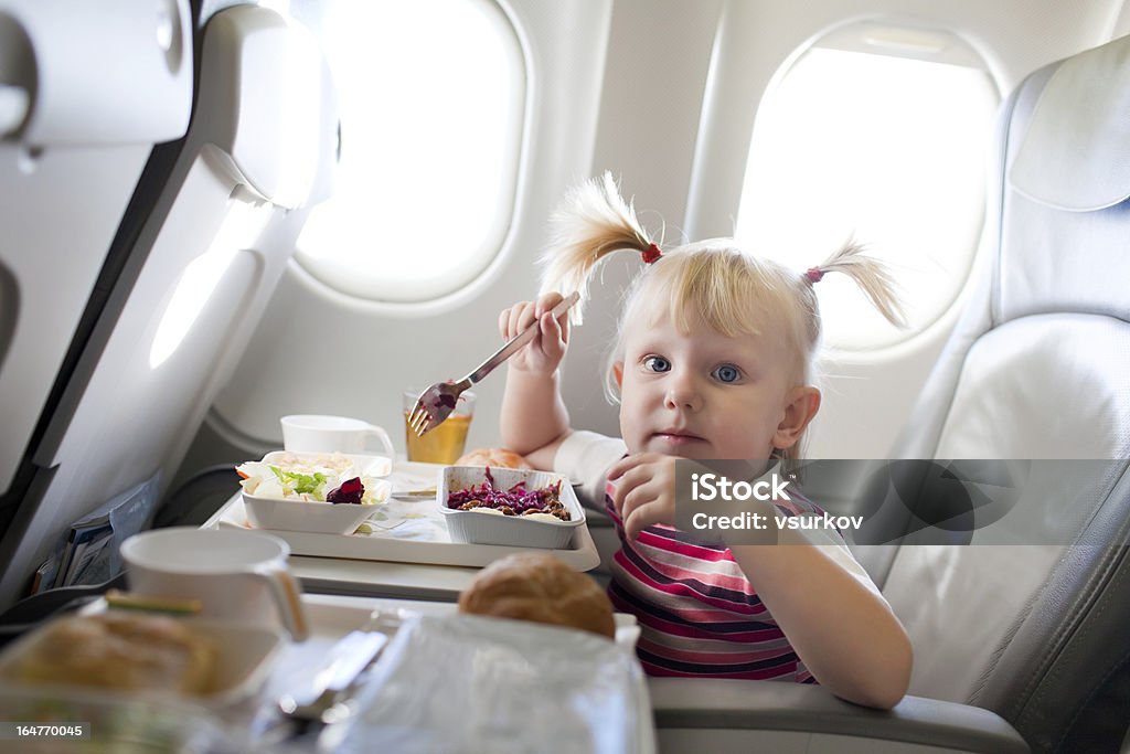 girl eating in the airplane small girl eating in the airplane Air Vehicle Stock Photo