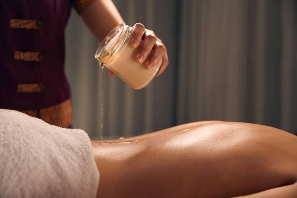 istock Massotherapist preparing woman for aromatherapy candle massage session 1647731350
