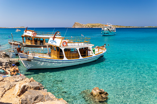 Large boats full of tourists exploring the clear waters and hot, dry coastline in Kolokitha, near Elounda, Crete