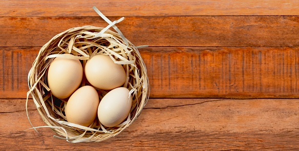 A close-up of eggs in a basket on a wooden surface