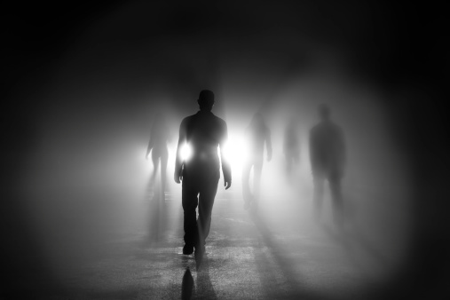 Silhouettes of people walking into light