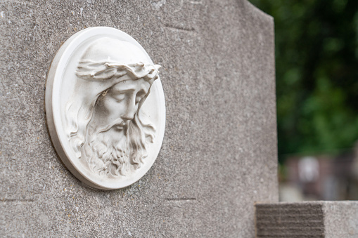 On a dark day, a tombstone shows Jesus face