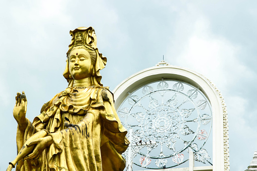 Golden Guanyin statue that is being built on a tall building for Thai and Chinese people People all over the world worship with backgrounds. White and gray clouds that look warm during the rainy seaso