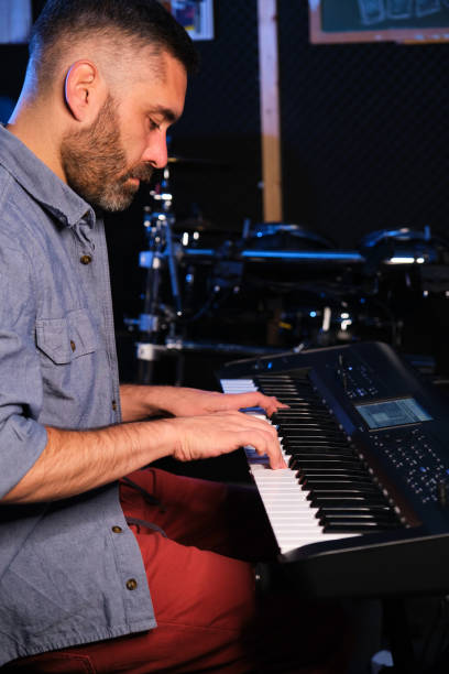 istock Musician man playing keyboard synthesizer piano in a recording studio. 1647853424