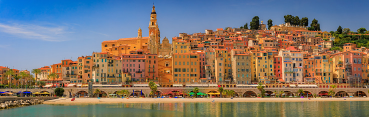 Colorful house facades above the Mediterranean Sea and beach in Old Town Vieille Ville of Menton on the French Riviera, South of France on a sunny day