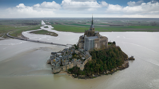 Mont-Saint Michel,France,March 11 2023:A senior tourist taking photos from hotel window on Mont-Saint Michel on a rainy day. Mont-Saint Michel is one of the most popular attractions in France to international tourists.
