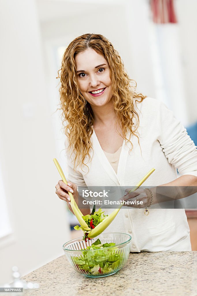 Mulher sorridente mostrando salada na cozinha - Foto de stock de 30 Anos royalty-free