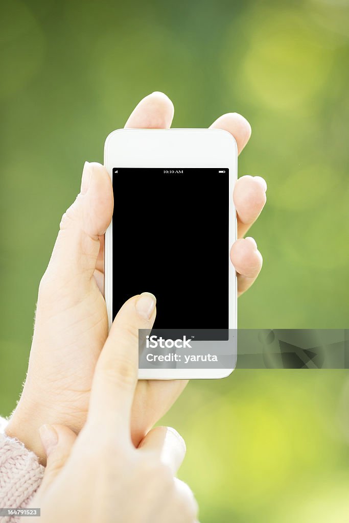 Woman holding smartphone Woman holding smartphone in hands against green spring background Adult Stock Photo