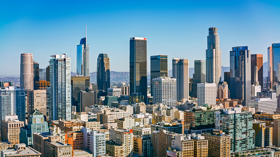 An aerial view of San Francisco on a beautiful blue sky day. The city skyline is filled with recognizable skyscrapers. The San Francisco Bay is visible in the background.