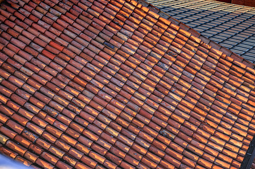 Tiles of red shades a bit weathered on slant roof top, abstract backgrounds