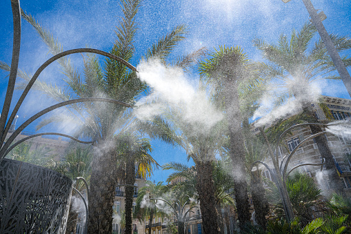 Spraying water sprinklers in a public park during heat wave in Spain. High resolution 42Mp outdoors digital capture taken with SONY A7rII and Zeiss Batis 25mm F2.0 lens