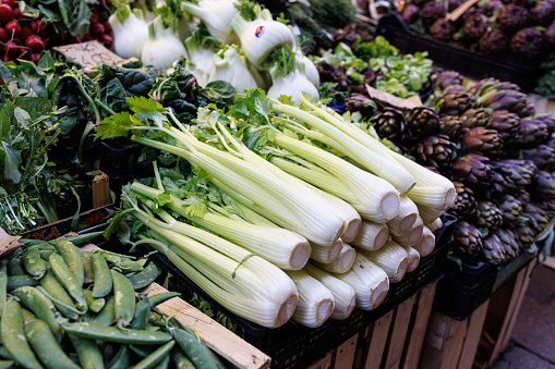 Bunches of celery sticks and artichoke on traditional green market stall in Bologna, Italy