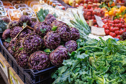Artichoke in crate and green leaf vegetables on traditional green market stall in Bologna, Italy