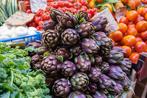 Bunch of fresh artichoke and other vegetables on traditional food market stall in Bologna, Italy