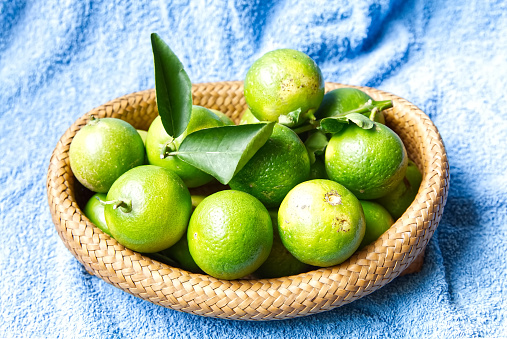 Thai lemons are in a basket on a table covered with blue cloth