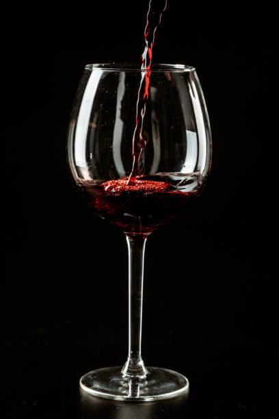 istock Red wine being poured in a wine glass on a dark background 1648022837