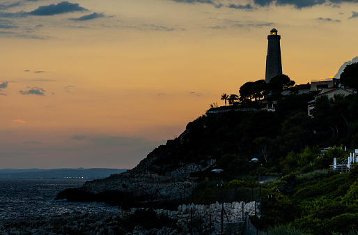 Saint Jean Cap Ferrat, France - August 5, 2022: Sunset over rocky coast of Cap Ferrat cape with Phare Lighthouse near Saint-Jean-Cap-Ferrat resort town and Nice at French Riviera