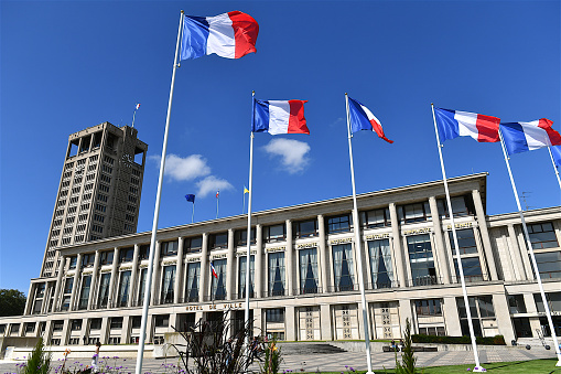 Le Havre, France-08 25 2023: Le Havre town hall building and french flags. The town hall building was designed by architect A.Perret after been destroyed during world war two.