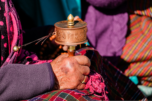 close-up hand of old bhutanese woman praying in Bhutan. Hand holding tibetan prayer wheel. High quality photo