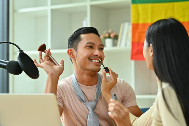 mujer joven aplicando brillo de labios en los labios de sus amigos. estilo de vida lgbtq y concepto de amistad - gay pride flag audio fotografías e imágenes de stock