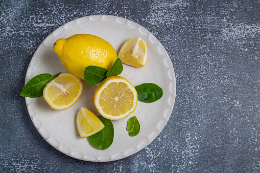 bright yellow lemon Half cut and sliced in a white plate on a colored background.