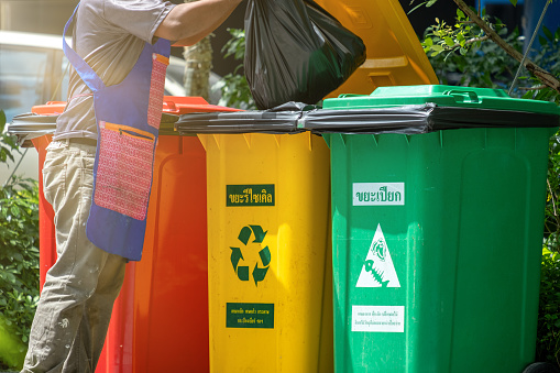 People throwing some garbage into a recycle bin. Recycling concept by the man seperate waste before disposal to save the environment.