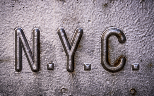 Close-up on the NYC acronym for New York City, on a corroded manhole cover in Manhattan.
