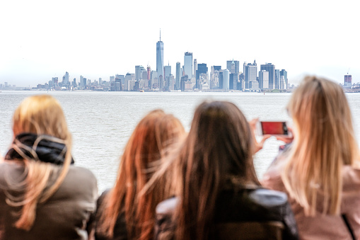 Selective focus, with tourists in the foreground defocused, and the New York City skyline in the distance in focus.