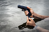 Reloading a pistol with male hands in water, close-up photo.