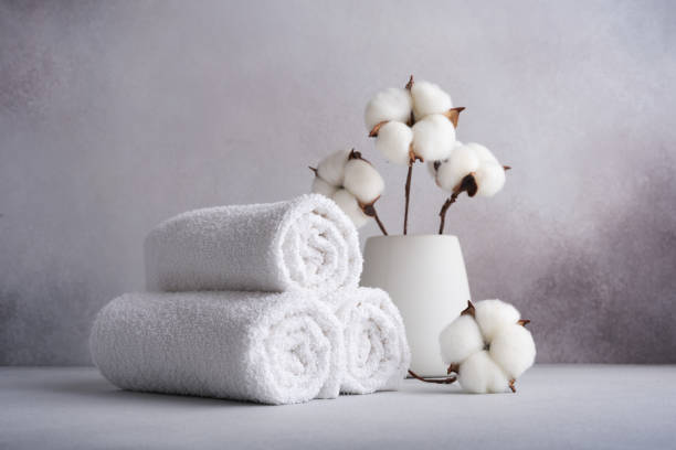Stack of rolled white towels with cotton flowers