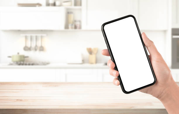 istock Kitchen table wooden board tray smartphone hand screen template 1648095099