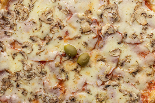 Extreme close-up of pizza with mushrooms meat and cheese isolated on a blue background