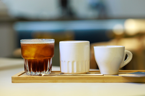 Cappuccino coffee with latte art on wooden table. Black cup, beautiful milk foam and macaroon cookies. Soft focus.