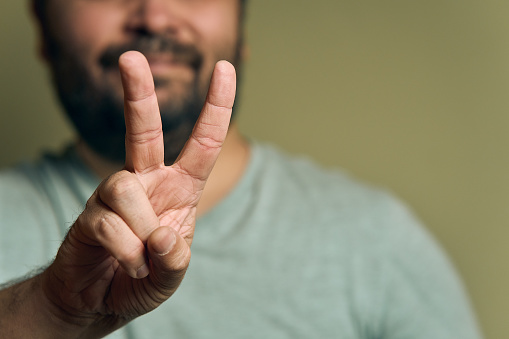 A bearded European man shows hand sign victory