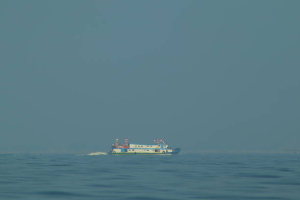 passenger ships and fishing boats, equally visible above the vast ocean. against a background of blue sea and blue clouds.