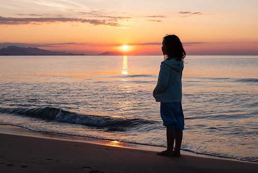 Sunrise over the sea. On the beach girls 7 years old watching the sunrise.