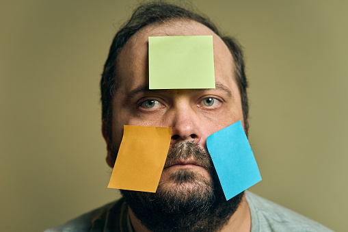 Facial portrait of a man with a beard looking into the frame and covered with blank paper stickers