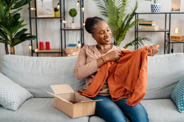 istock Young Woman Unboxing A Package With A New Shirt She Ordered Online 1648181881