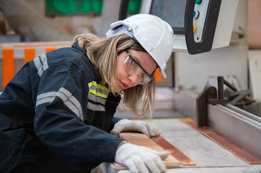 woman wearing safety uniform and hard hat working quality inspection of wood products at workshop manufacturing wooden. female carpenter worker wood warehouse industry.