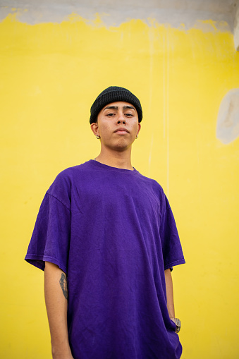 Portrait of a young Mexican man looking at the camera. Yellow background