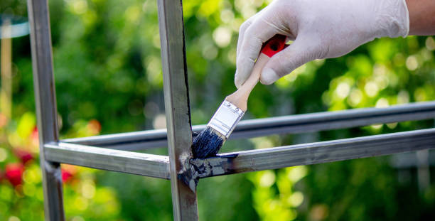 istock a man paints metal with black paint with a brush 1648191580