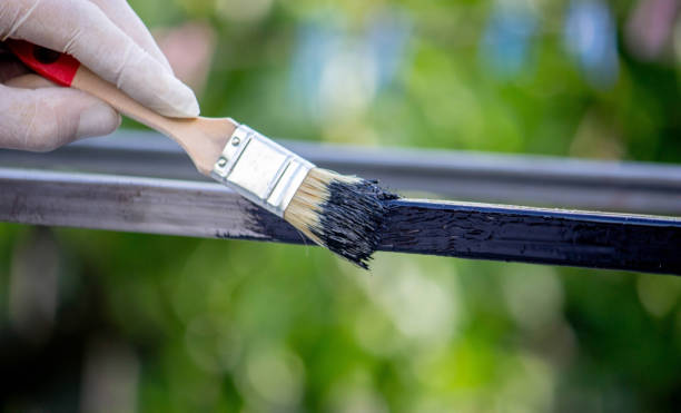 istock a man paints metal with black paint with a brush 1648191583