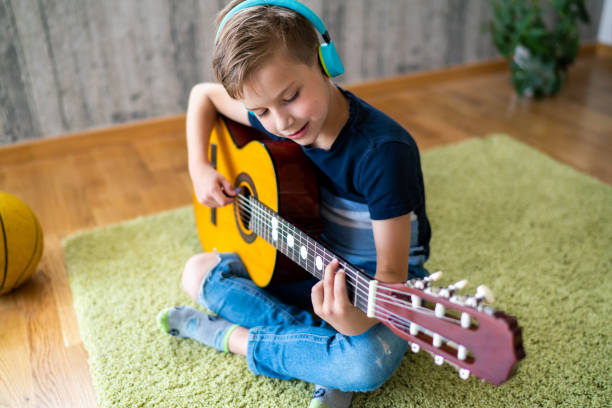 istock Boy playing acoustic guitar at home 1648191896