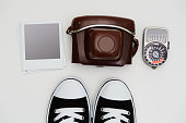 Vintage SLR camera, lightmeter and sneakers with some blank polaroid-like frames on white background