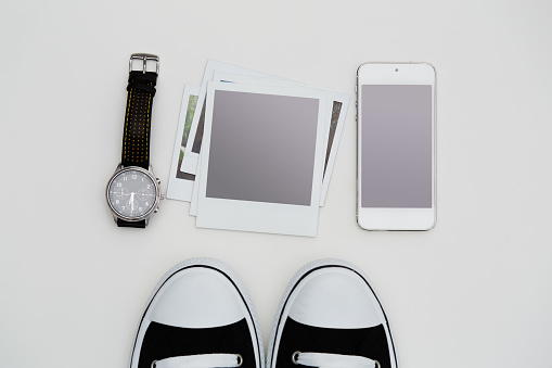 Hipster culture items. Sneakers, phone, blank polaroid-style photographs and a wrist watch flat lay on white background