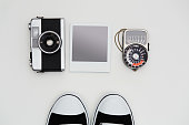 Vintage SLR camera, lightmeter and sneakers with some blank polaroid-like frames on white background