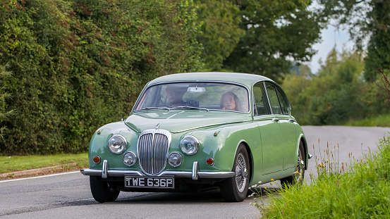 Whittlebury,Northants,UK -Aug 27th 2023:1968 green Daimler V8 250  car travelling on an English country road