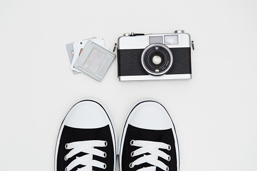 Young photographer ready to shoot. Hipster items. Film camera and sneakers with some old dia slide frames on white background